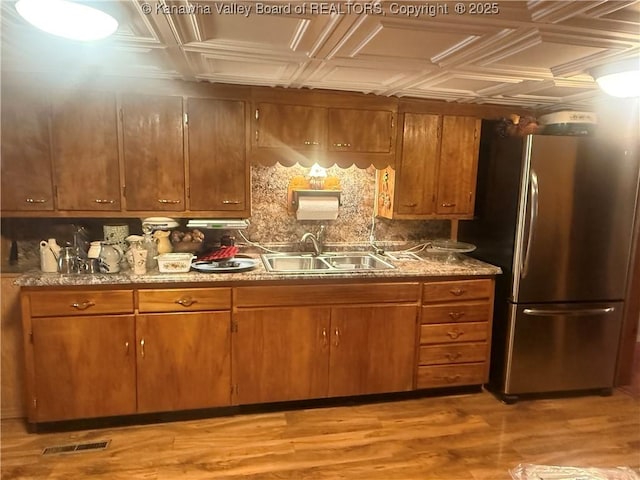 kitchen with tasteful backsplash, visible vents, freestanding refrigerator, an ornate ceiling, and a sink