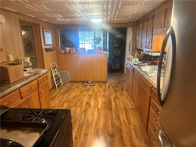 kitchen with light wood finished floors, brown cabinets, an ornate ceiling, and freestanding refrigerator