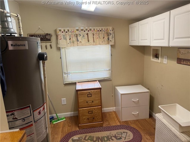 laundry room featuring baseboards, water heater, light wood-style flooring, hookup for a washing machine, and cabinet space