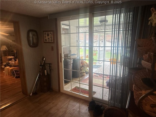 doorway to outside with a textured ceiling and wood finished floors