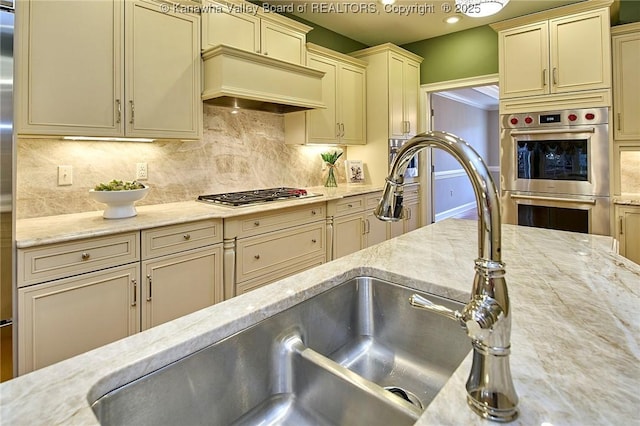 111 Graff Ln, Charleston, WV 25304 - kitchen with cream cabinets, appliances with stainless steel finishes, custom exhaust hood, backsplash, and light stone countertops