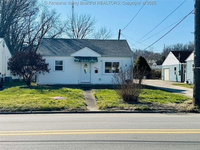 view of front of property with a front yard, an outbuilding, a garage, and a shingled roof