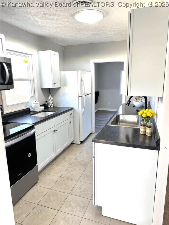 kitchen with a sink, dark countertops, appliances with stainless steel finishes, and white cabinets