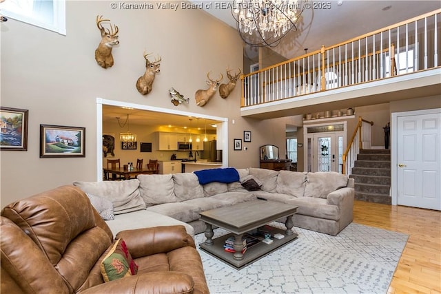 living room with stairway, wood finished floors, a chandelier, and a towering ceiling