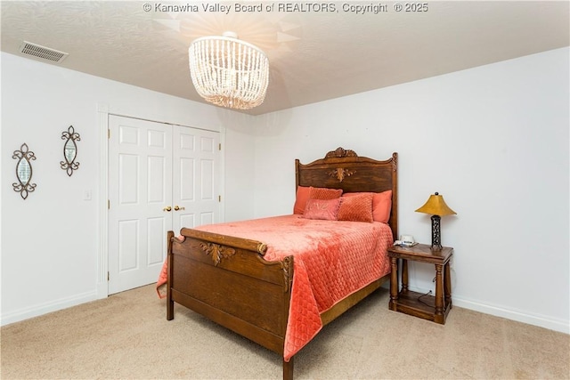 carpeted bedroom featuring a chandelier, baseboards, visible vents, and a closet