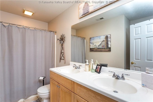bathroom with double vanity, toilet, visible vents, and a sink