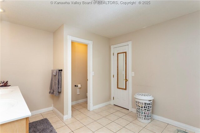 bathroom featuring double vanity, baseboards, and tile patterned flooring