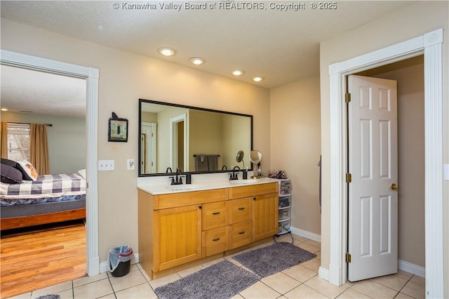 ensuite bathroom with double vanity, a sink, connected bathroom, and tile patterned floors