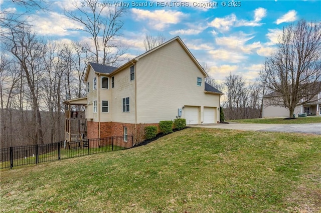 view of home's exterior with fence, driveway, brick siding, an attached garage, and a yard