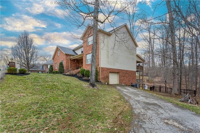 view of property exterior with brick siding, fence, aphalt driveway, a yard, and an attached garage