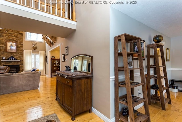 interior space with a textured ceiling, light wood finished floors, a high ceiling, and a fireplace