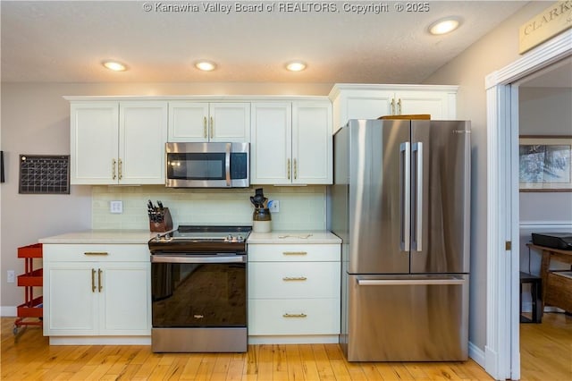 kitchen featuring light countertops, appliances with stainless steel finishes, white cabinets, and light wood-style floors