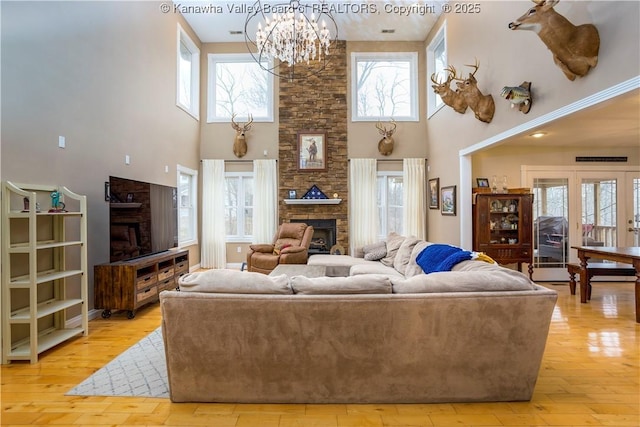 living area featuring a towering ceiling, an inviting chandelier, and a fireplace
