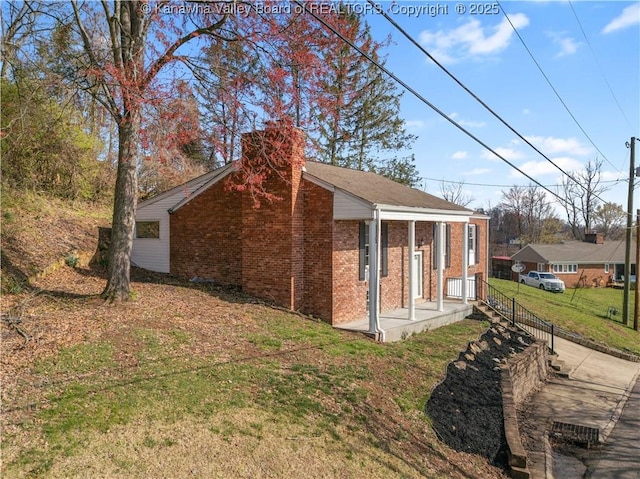 view of home's exterior with a lawn, brick siding, and a chimney