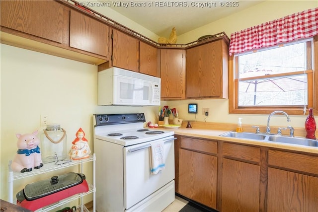 kitchen featuring light countertops, a sink, brown cabinets, and white appliances