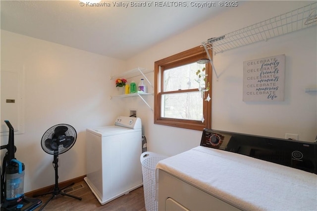 washroom featuring baseboards, washing machine and dryer, wood finished floors, and laundry area