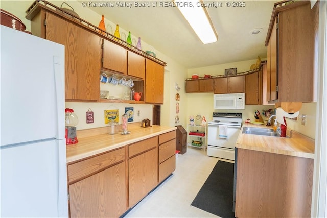 kitchen featuring light countertops, a sink, light floors, brown cabinets, and white appliances