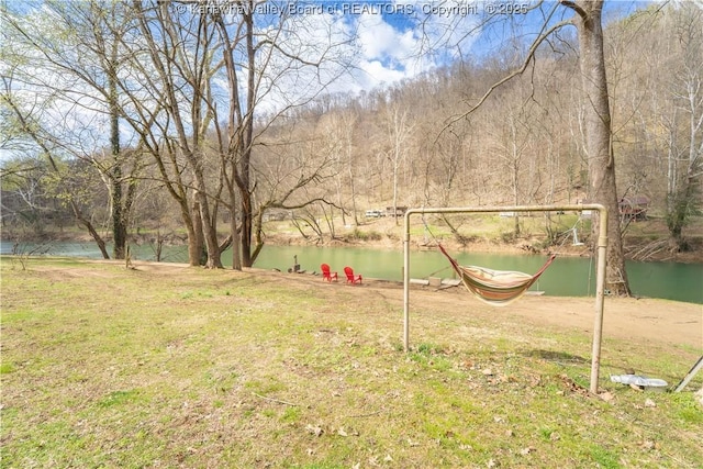 view of yard featuring a water view and a wooded view
