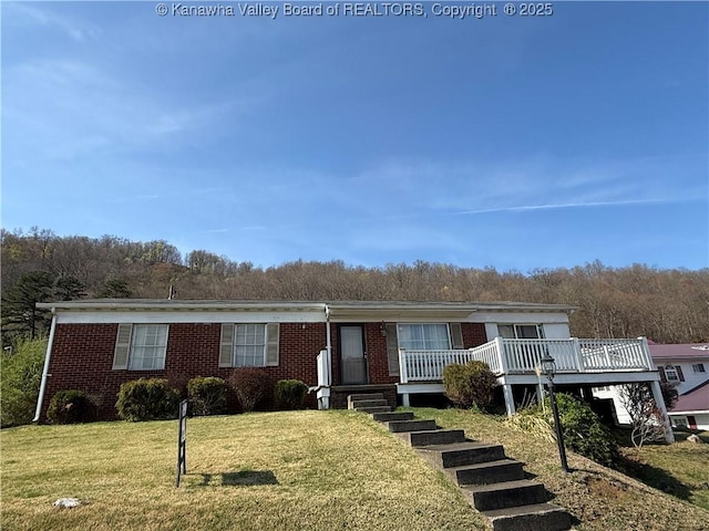 view of front of house with brick siding, a front yard, and stairs