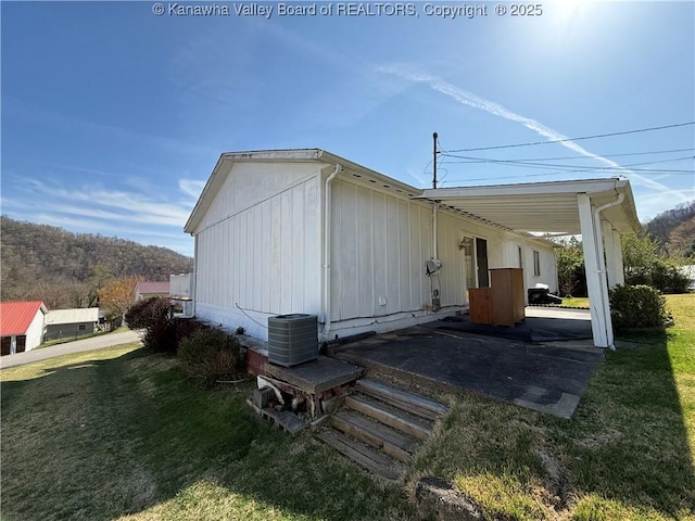 view of side of home featuring an attached carport, central air condition unit, and a lawn