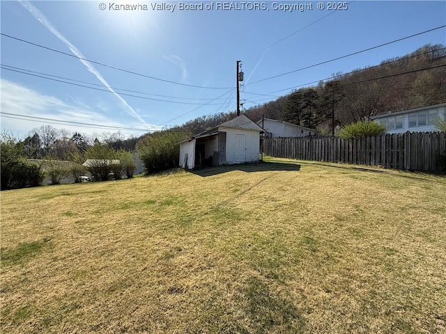 view of yard with an outbuilding, fence, and a shed