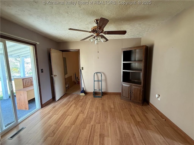 unfurnished bedroom featuring baseboards, visible vents, light wood-style flooring, and a textured ceiling