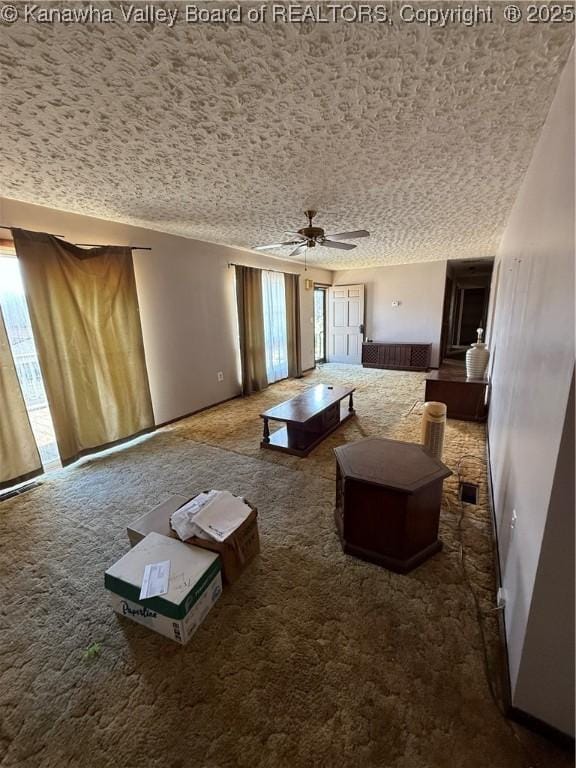 unfurnished living room with ceiling fan, carpet flooring, and a textured ceiling
