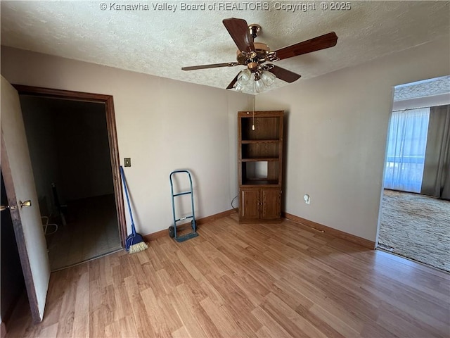 unfurnished room with a ceiling fan, light wood-style floors, and a textured ceiling