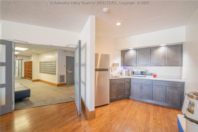 kitchen featuring light countertops, light wood-type flooring, stainless steel appliances, a textured ceiling, and visible vents