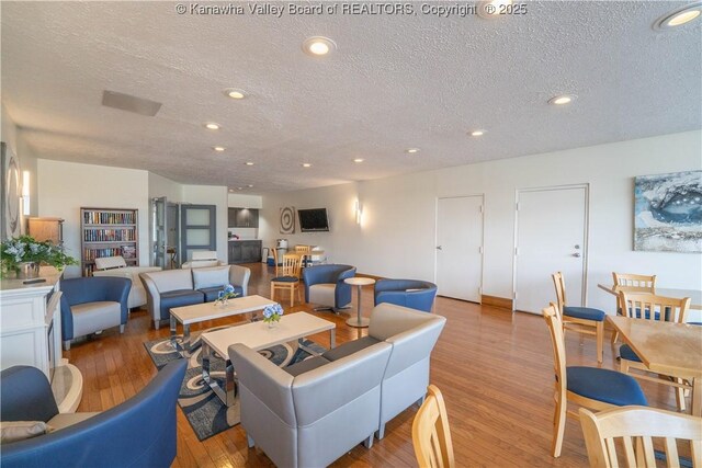 living area featuring a textured ceiling, wood finished floors, and recessed lighting