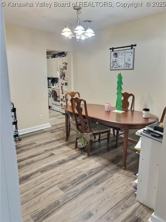 dining space featuring baseboards, a notable chandelier, and light wood-style floors