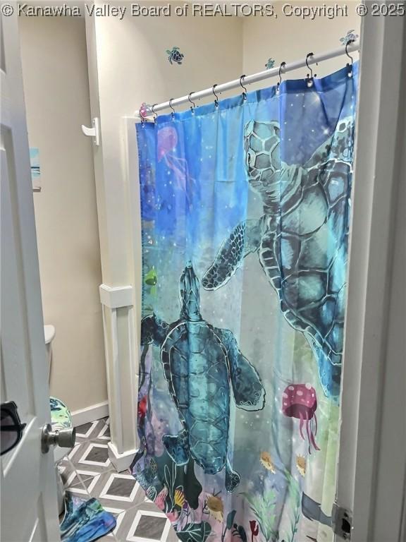 full bath with a shower with shower curtain and baseboards
