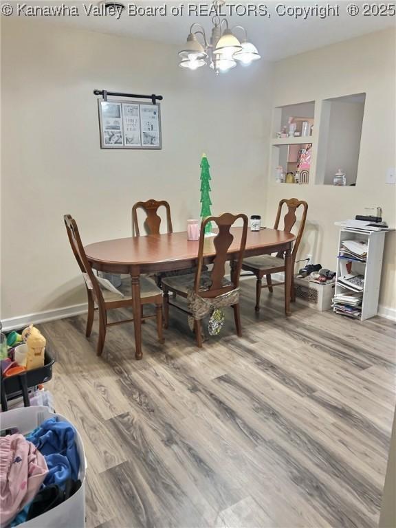 dining space with baseboards, wood finished floors, and a chandelier