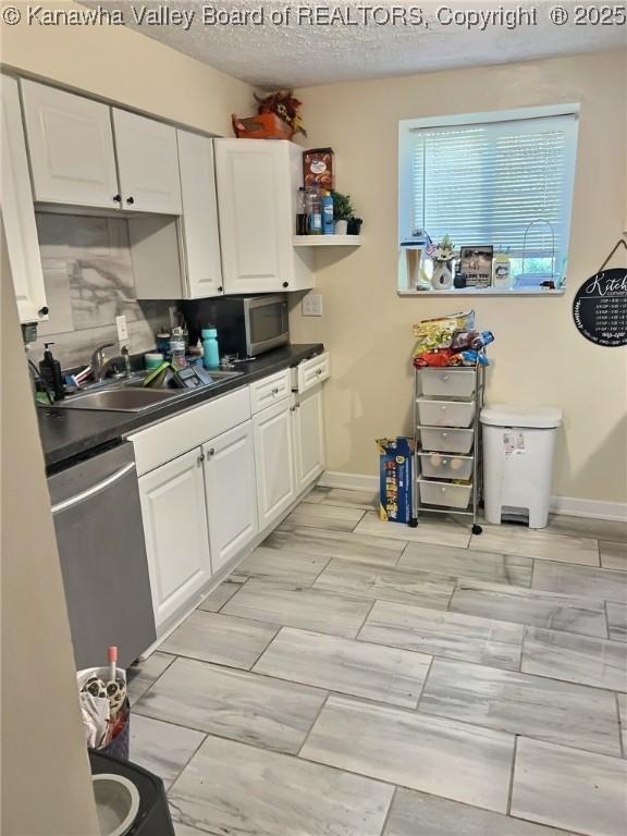kitchen with white cabinets, a sink, stainless steel appliances, and dark countertops