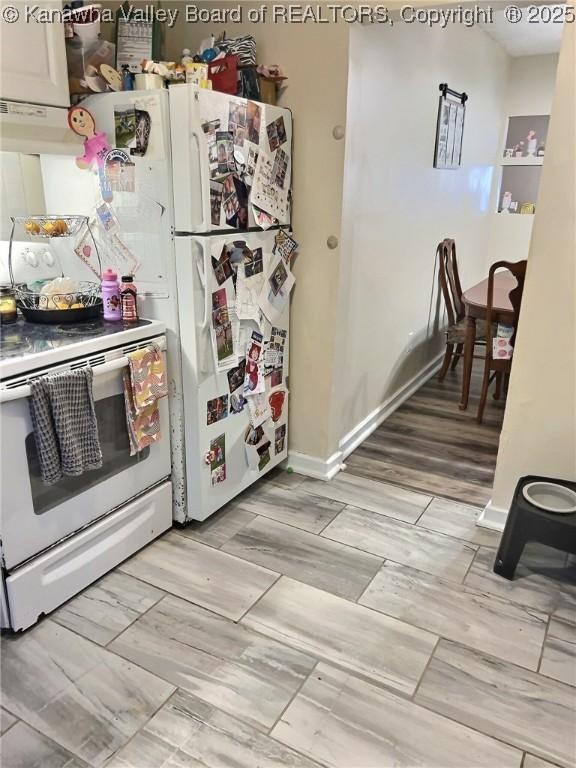 kitchen featuring white electric range oven, baseboards, and under cabinet range hood