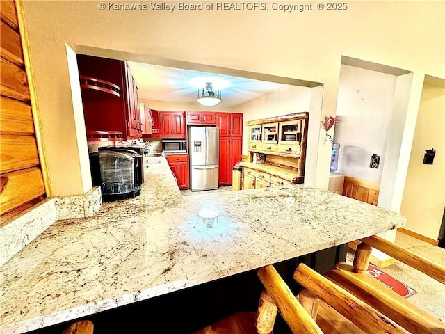 kitchen with range hood, a peninsula, dark brown cabinets, stainless steel appliances, and a breakfast bar area