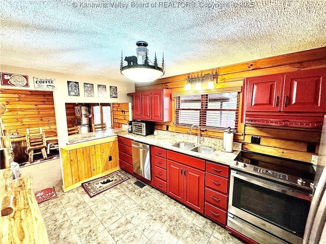 kitchen featuring stainless steel appliances, a textured ceiling, a sink, and reddish brown cabinets