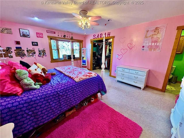 carpeted bedroom with ensuite bathroom, a closet, a ceiling fan, a spacious closet, and baseboards