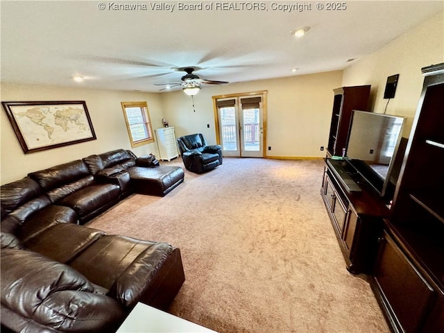 living area with baseboards, a ceiling fan, and light carpet