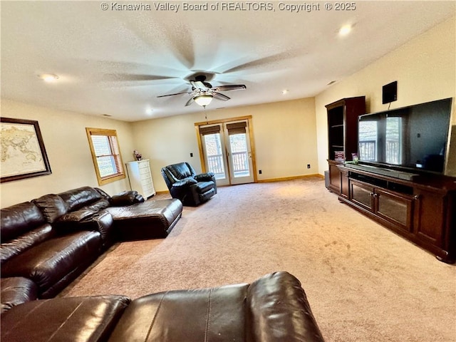 living room featuring baseboards, light colored carpet, a ceiling fan, and a textured ceiling