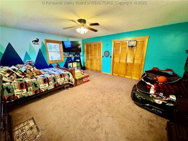 carpeted bedroom featuring multiple closets, a ceiling fan, baseboards, and a textured ceiling