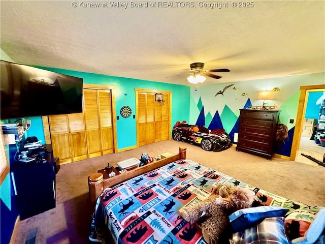bedroom featuring baseboards, ceiling fan, carpet, a textured ceiling, and multiple closets