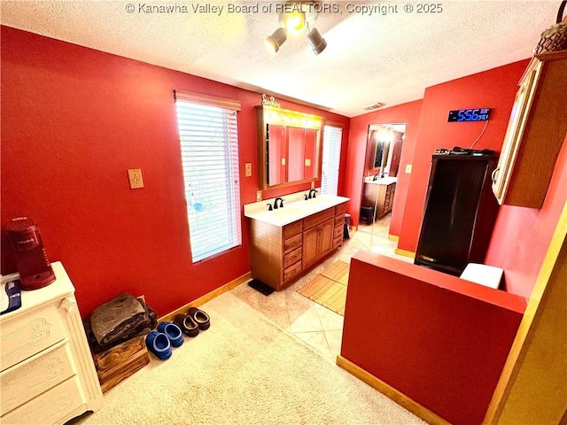 bathroom featuring a textured ceiling, vanity, vaulted ceiling, tile patterned floors, and baseboards