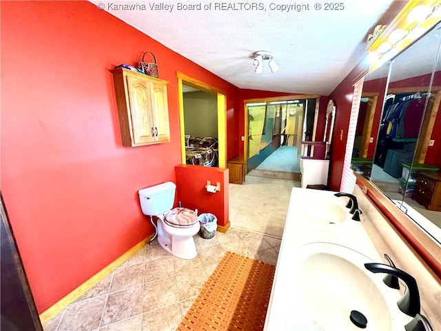 full bathroom featuring a sink, baseboards, double vanity, and a textured ceiling
