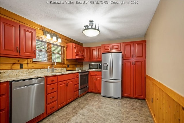 23 Mindia Ln, Alum Creek, WV 25003 - kitchen with stainless steel appliances, a sink, wooden walls, light stone counters, and wainscoting