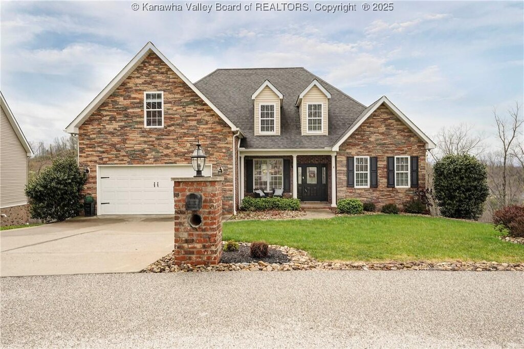 view of front of property featuring a front yard, stone siding, an attached garage, a shingled roof, and concrete driveway