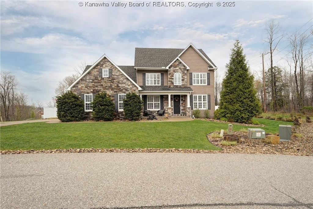traditional-style home with a shingled roof, stone siding, and a front lawn