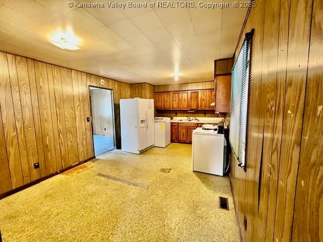 161 Kanawha Ave, Smithers, WV 25186 - kitchen featuring white refrigerator with ice dispenser, separate washer and dryer, brown cabinets, wood walls, and light countertops