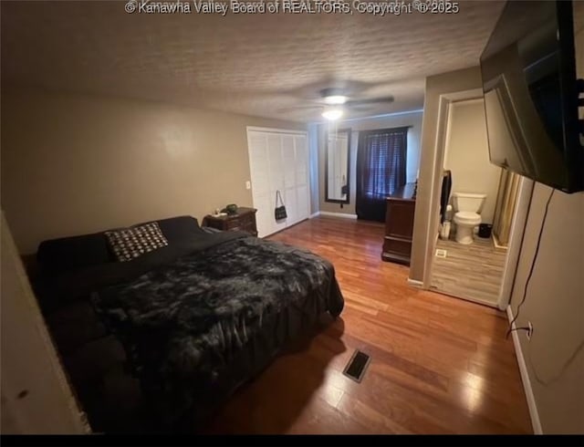 bedroom featuring connected bathroom, a textured ceiling, a ceiling fan, and wood finished floors