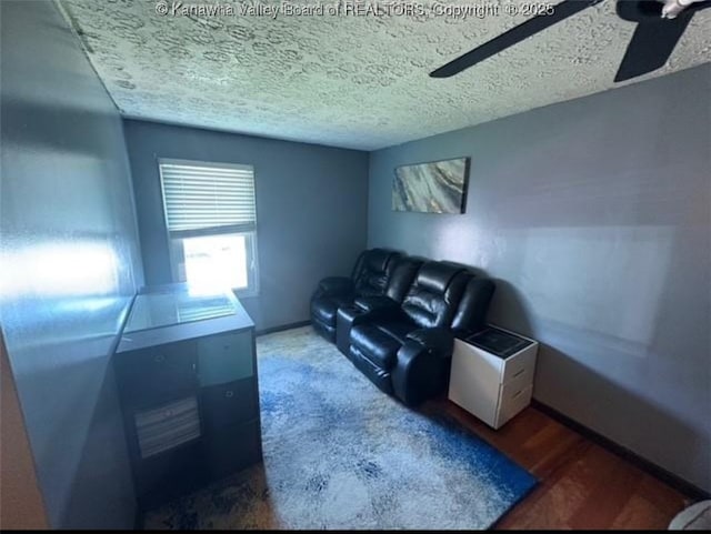 living area with a ceiling fan, wood finished floors, and a textured ceiling